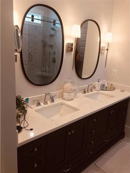 主浴室有一个大的深色木质梳妆台，配有双水槽和椭圆形镜子。