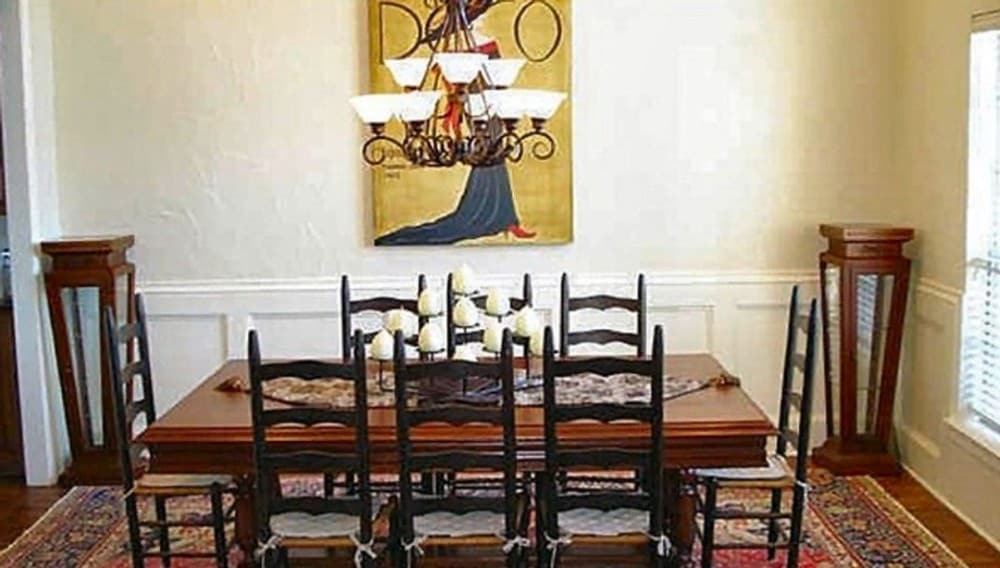正式餐厅8-seater餐桌,一个经典的小地毯,米黄色的墙壁装饰艺术品和白色护墙板。