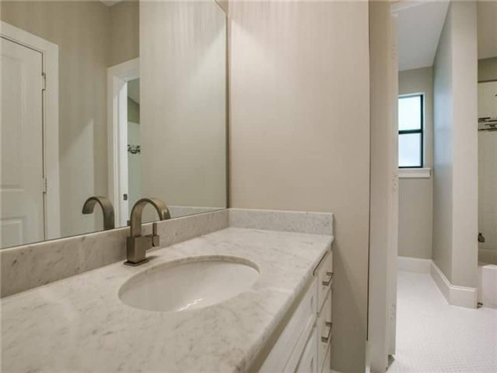 主浴室有白色的梳妆台和一面巨大的无框镜子。