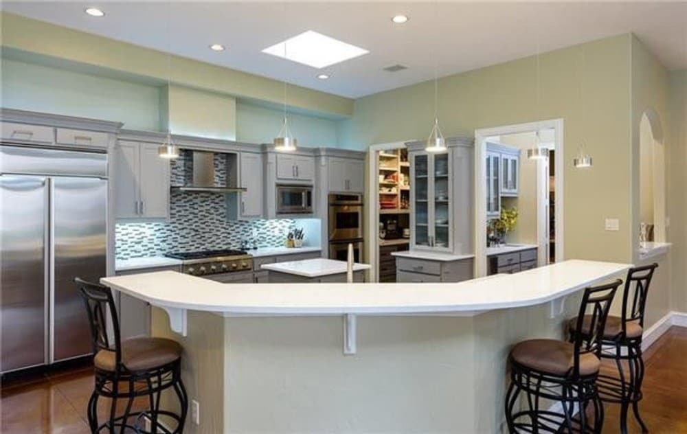 厨房设有两个岛台、白色橱柜、一扇天窗和一间管家的食品储藏室。