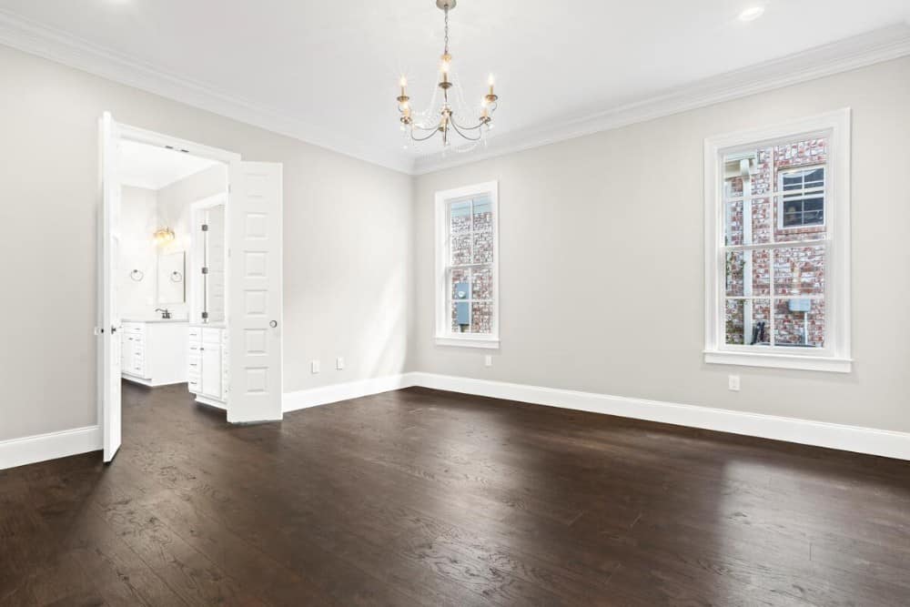 主卧室采用天然硬木地板，双扇白色门通往主浴室。