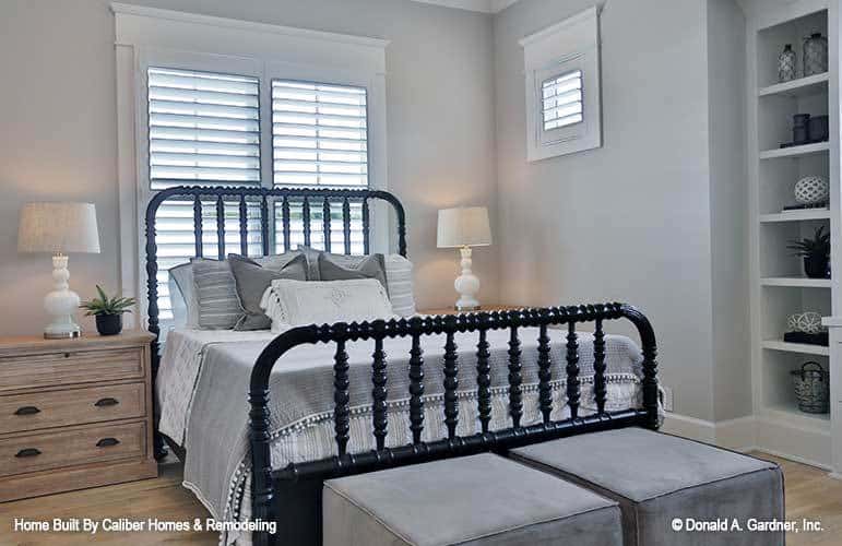 卧室有一张铁床，天鹅绒的脚垫，和白色的嵌入式装饰与各种装饰。