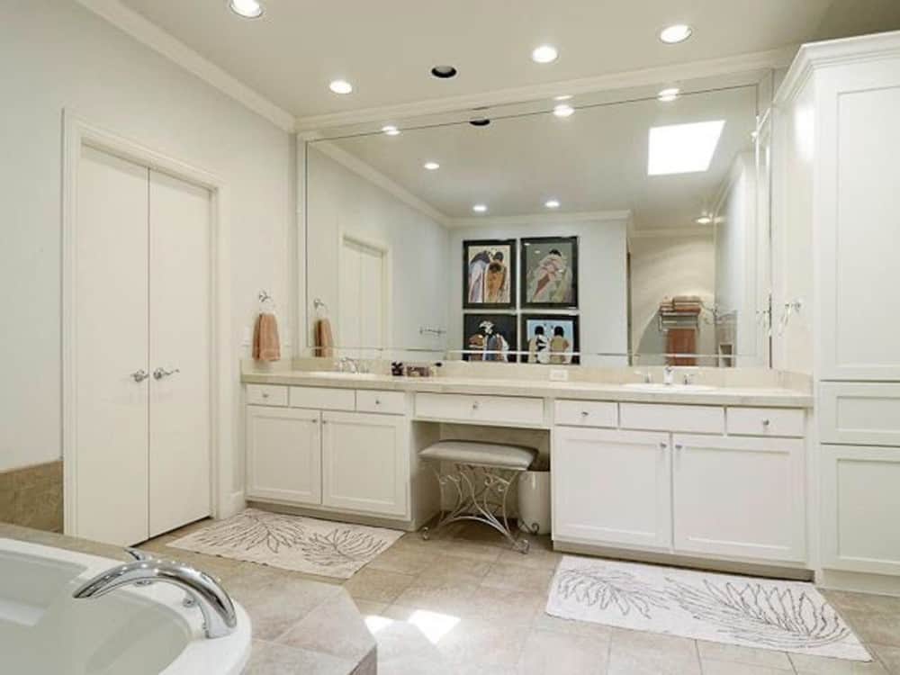 主浴室大双水槽虚荣和一个大壁橱隐藏在白色的双扇门后面。