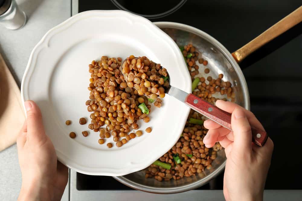 刚煮熟的棕色扁豆正从锅里移到盘子里。