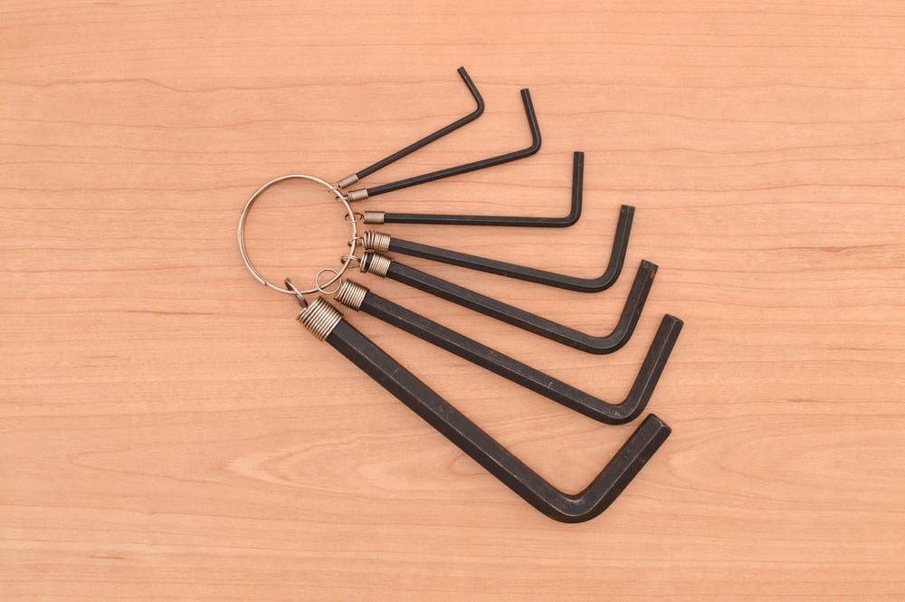 这是木桌上的一套深色六角扳手，由一个钥匙圈连接在一起。