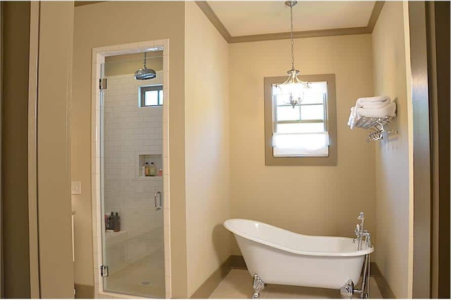 主浴室里有一间爪形浴缸和一间步入式淋浴间，淋浴间配有一条瓷砖长凳和一扇玻璃铰链门。