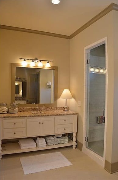 主浴室包括一个白色梳妆台，上面有一面镜框镜子和温暖的玻璃烛台。