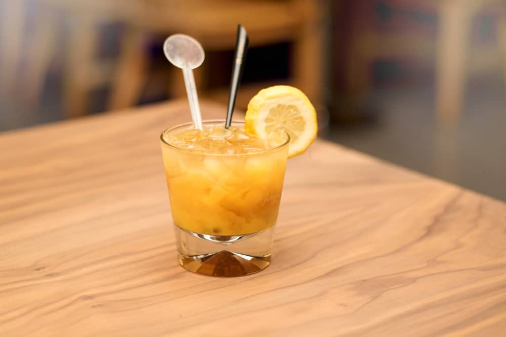 这是一种模糊的橘色肚脐鸡尾酒，放在木桌上。