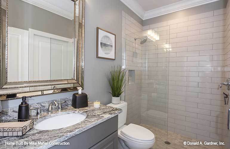 浴室有一个洗手台，一个马桶，和一个步入式淋浴间，白色的地铁瓷砖墙。
