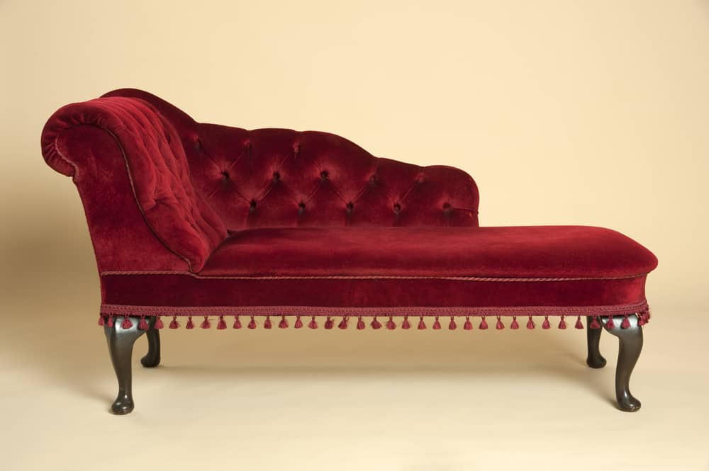 这是一个暗红色天鹅绒簇绒躺椅躺椅深色木腿。