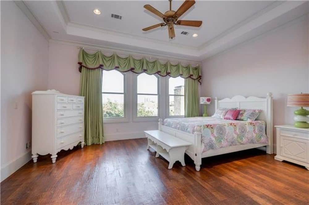 这间卧室有托盘天花板和白色家具，由天然硬木地板软化。