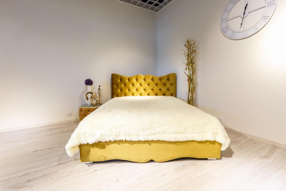 角落里是一张黄色的簇绒切斯特菲尔德式床。