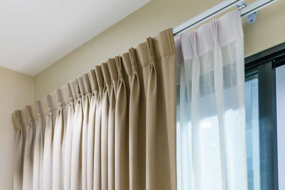 这些是褶皱米色和白色的透明窗帘，带有吊环和小孔。