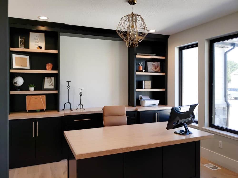 家庭办公室有黑色的橱柜，浮动的架子，木制的桌子搭配皮革转椅。