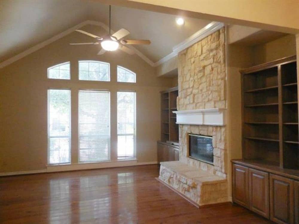 家庭娱乐室有拱形天花板，硬木地板，和一个石质壁炉，两侧有木制嵌壁柜。