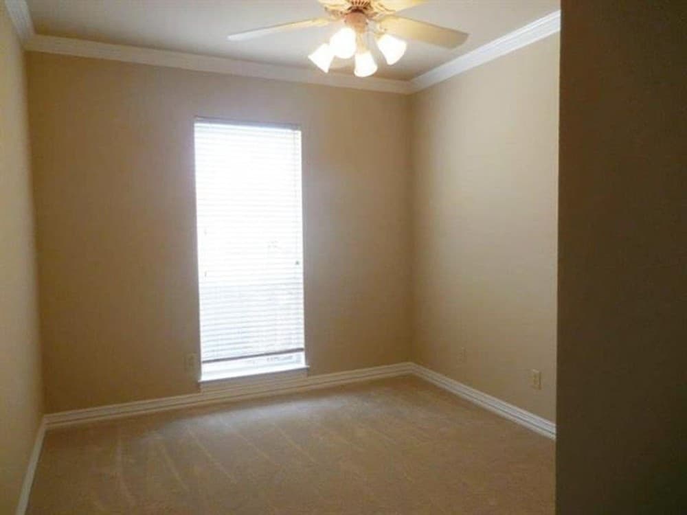 主卧室铺有地毯地板，传统的风扇和温暖的灯，米黄色的墙壁上有白色的装饰。