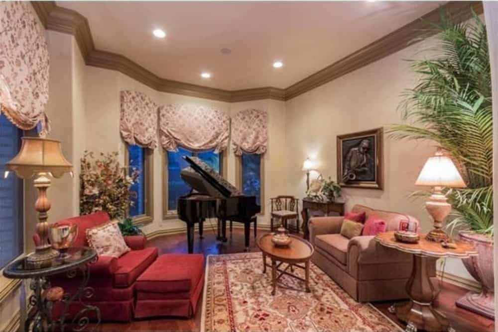 客厅里摆放着一架小型三角钢琴、舒适的座椅、一株高大的盆栽，还有一扇挂着罗马窗帘图案的飘窗。