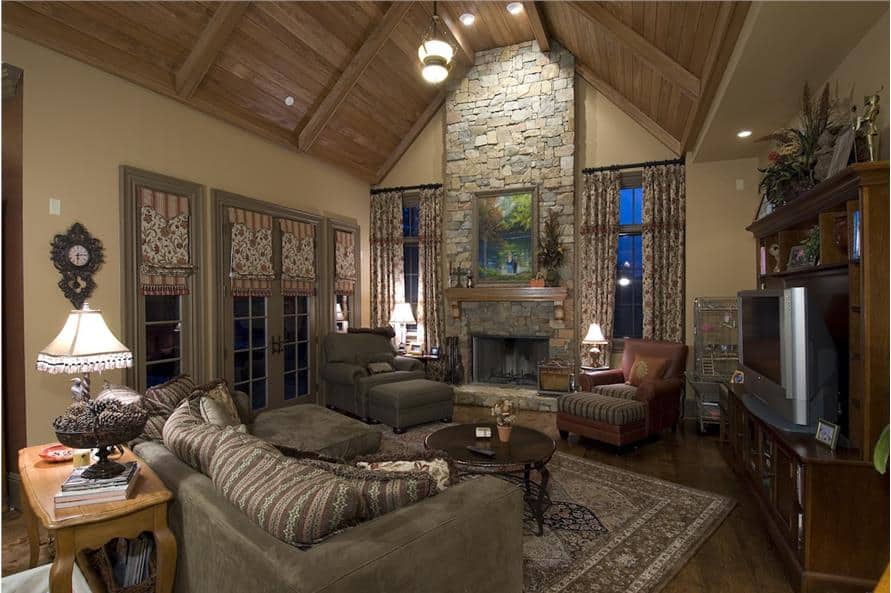 房间里有一座石头壁炉，一张灰色沙发，拱形天花板下有几把皮革躺椅，上面铺着木板。