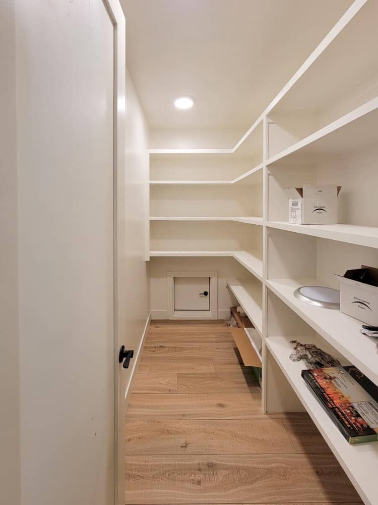 步入式食品储藏室有宽阔的木板地板和内置货架，与白墙融为一体。