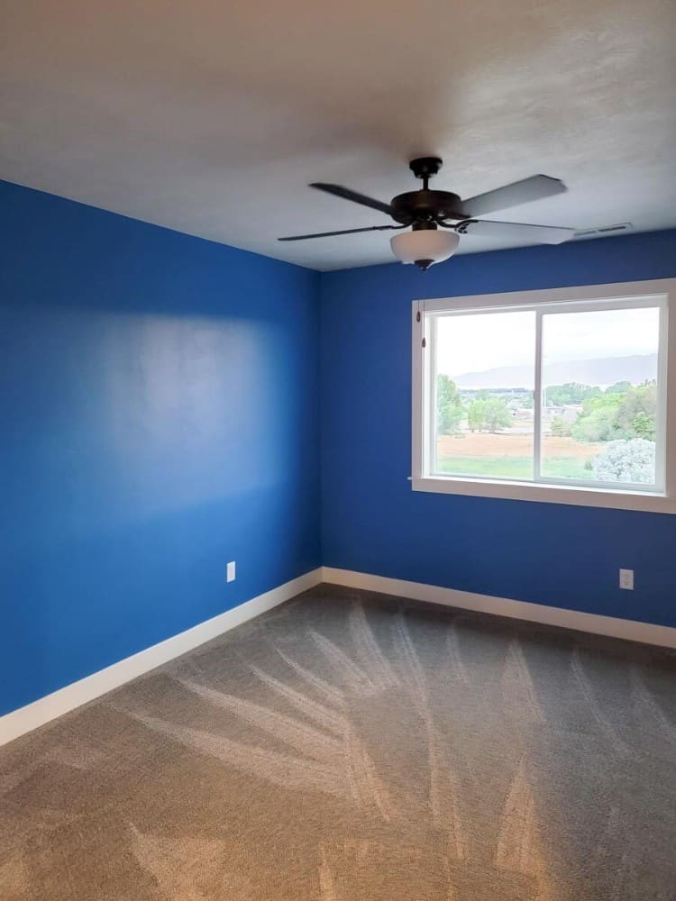 这间卧室有宝蓝色的墙壁，一座铁吊扇，还有可以俯瞰广阔环境的滑动玻璃窗。