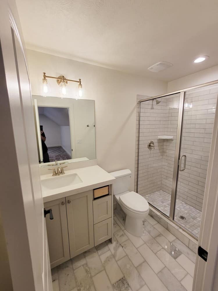 这间浴室配有洗手台、马桶和一个带滑动玻璃门的步入式淋浴间。