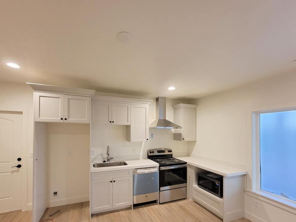 小厨房有硬木地板，下置水槽，白色橱柜与白墙融为一体。