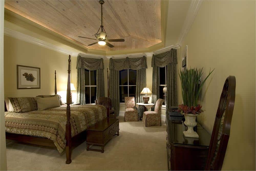 主卧室有一张四柱床，一个带凹槽的休息区，托盘天花板覆盖着轻木板。