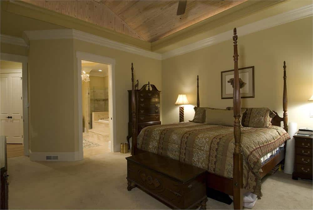 主卧室里还有一间私人浴室、一个深色木质梳妆台和一张配套的储物凳，与四柱床相映成趣。
