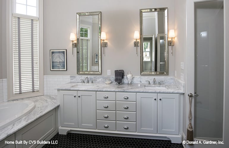 主浴室有一个落地式浴缸和一个双洗手池梳妆台，配有几面镀铬镜框镜子。