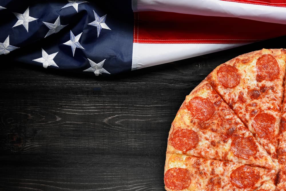 这是一个在木桌上有美国国旗的披萨。