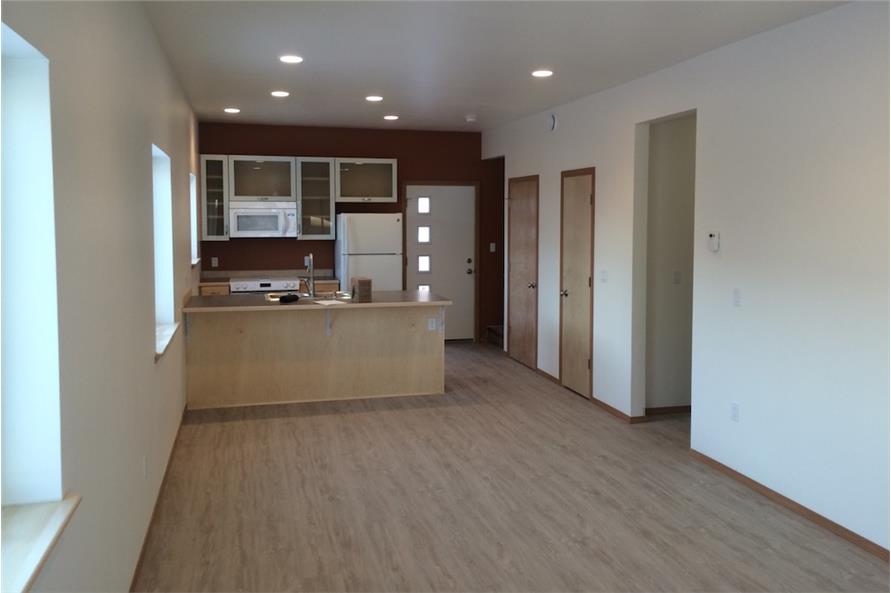 开放式的起居空间结合了客厅和厨房。它有浅色的硬木地板，米黄色的墙壁和白色的电器。