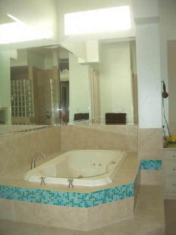 主浴室设有一个深浴缸，突出蓝色马赛克瓷砖。