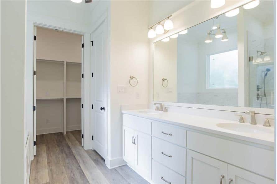 主浴室带有步入式衣橱和一个大梳妆台，配有双水槽，一面矩形镜子和玻璃烛台。