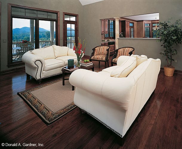 客厅里有花纹的圆形靠背椅和面向米色的沙发，配上一张深色的木头咖啡桌。