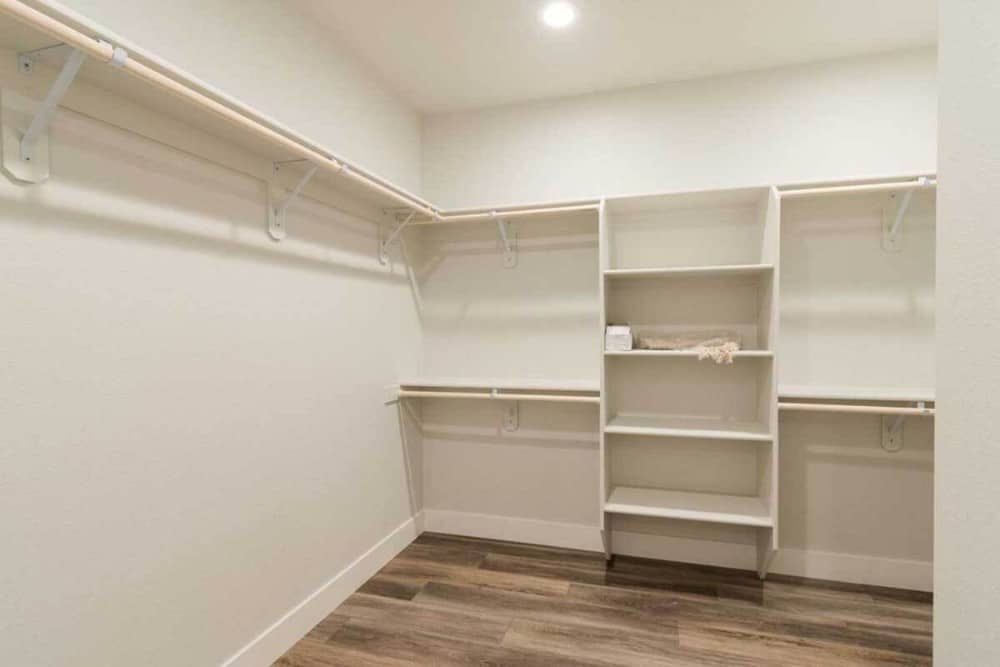 主间的步入式衣橱铺有硬木地板和嵌入式书架，与白墙融为一体。