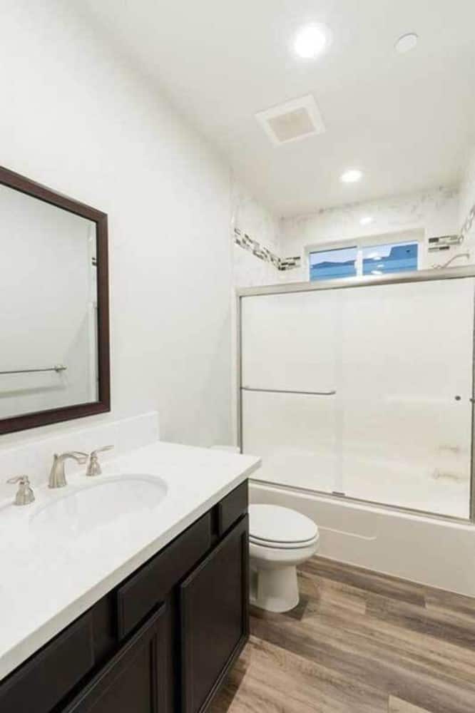 这个浴室配有洗手台、马桶和一个由滑动玻璃门封闭的浴缸和淋浴组合。