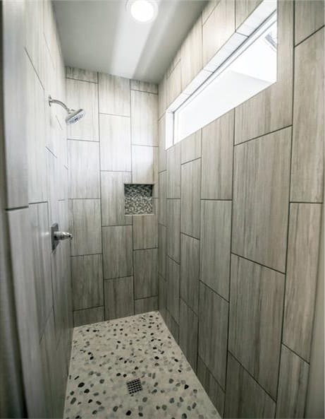 主浴室包括一间步入式淋浴间，带有瓷砖墙壁，鹅卵石地板，铬固定装置，以及一扇天窗，允许自然光进入。