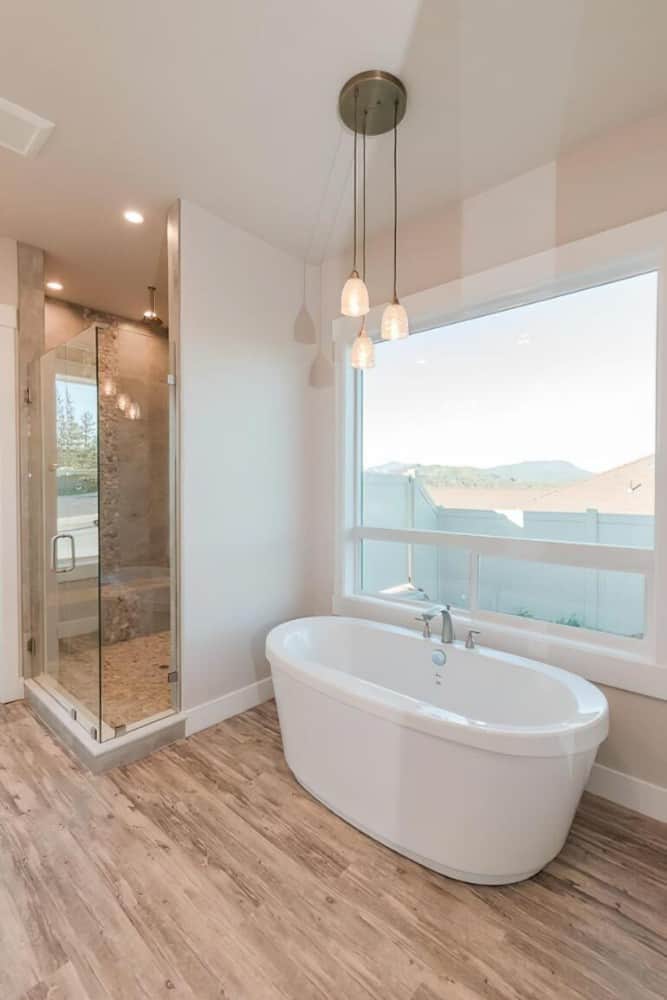 主浴室带一座独立浴缸和一间带瓷砖长凳和一扇玻璃铰链门的步入式淋浴间。