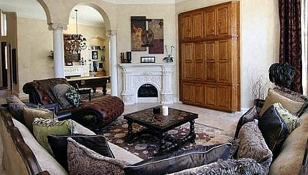 家庭娱乐室有一个角落壁炉，一个嵌入式橱柜，一簇皮革躺椅，l型沙发搭配深色木咖啡桌。