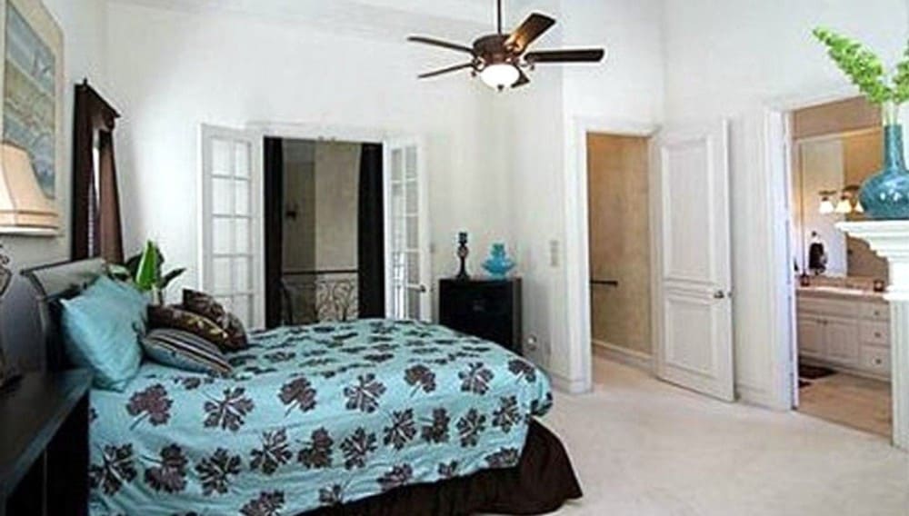 主卧室有一扇法式门，一间私人浴室，还有一张铺在地毯上的舒适的有裙边的床。