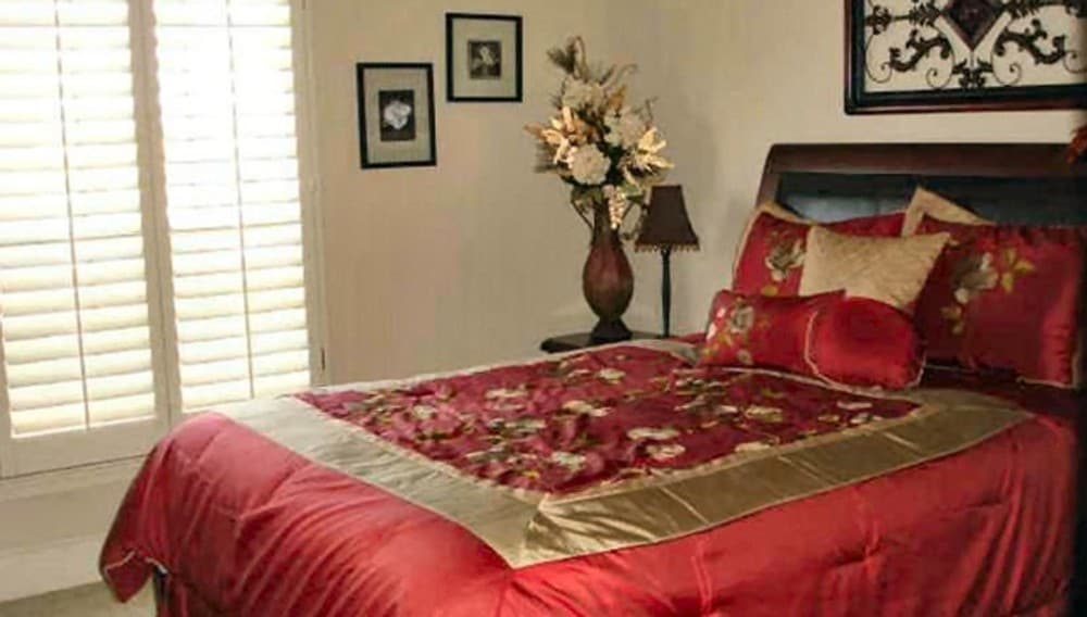 主卧室的特色是一张皮革床，上面装饰着红色丝绸床品。