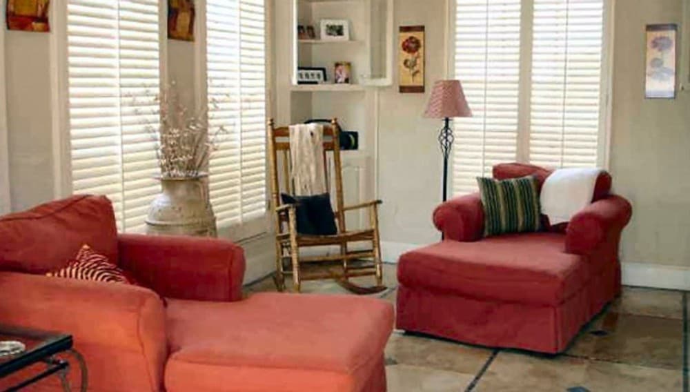 客厅里有红色躺椅，瓷砖地板上有一把木制摇椅。