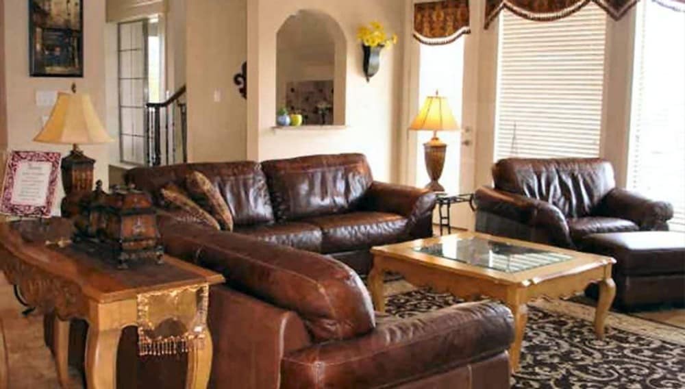家庭娱乐室提供棕色皮革座椅、木桌和有图案的区域地毯。