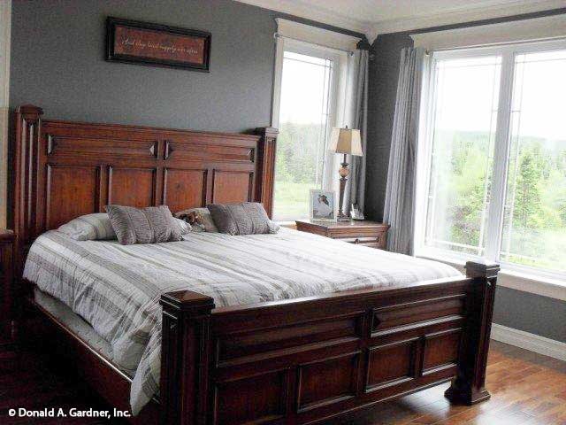 主卧室有灰色墙壁，木雕床，大窗户允许自然光进入。