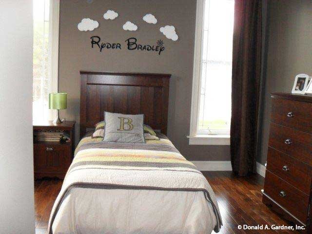 这间卧室有木制家具，硬木地板，灰色的墙壁装饰着云彩和名字贴纸。