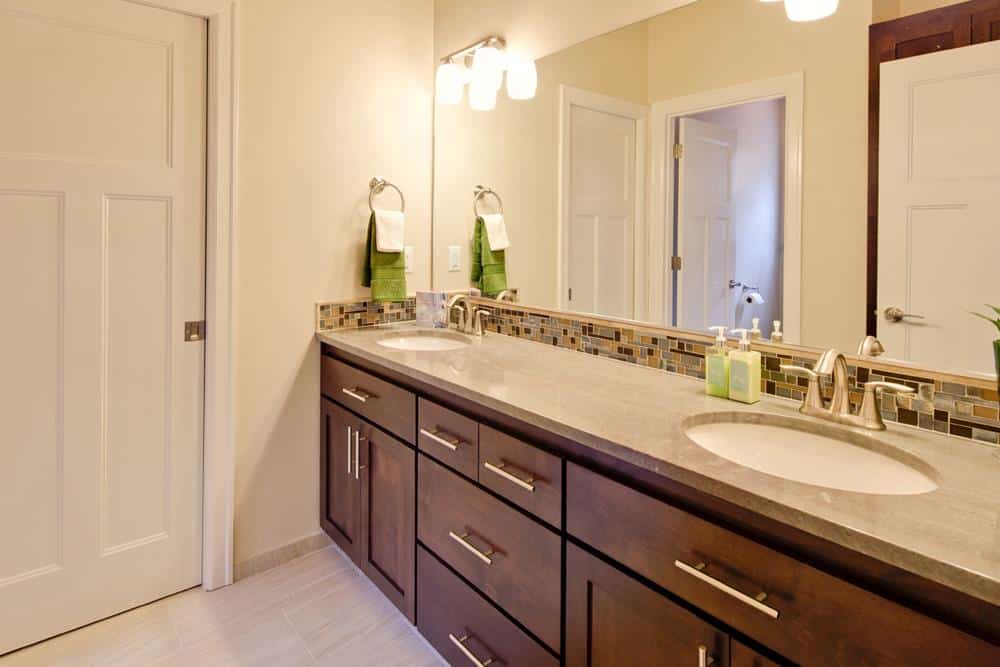 主浴室设有一个带双水槽的大型木制梳妆台和一面矩形无框镜子。