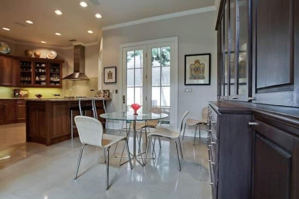 厨房对面是一个早餐角落，里面有一张圆形玻璃餐桌和几把编织椅子。