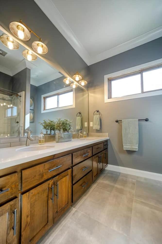 浴室带有双洗手池梳妆台，顶部有一面矩形镜子和暖壁灯。