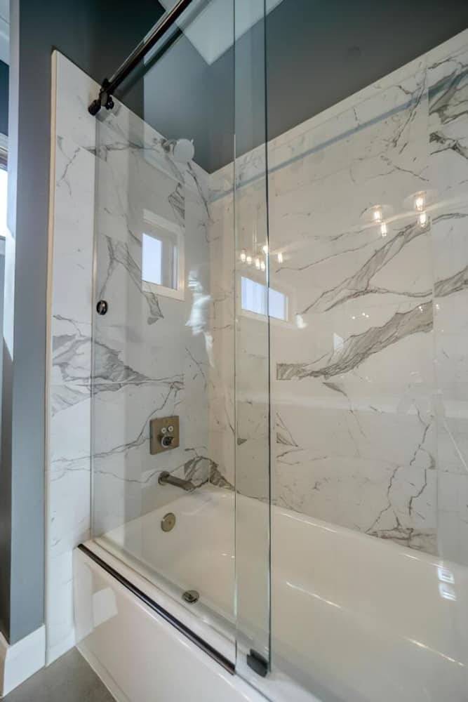 浴室包括一间浴缸和淋浴房，带有大理石瓷砖墙和滑动玻璃门。