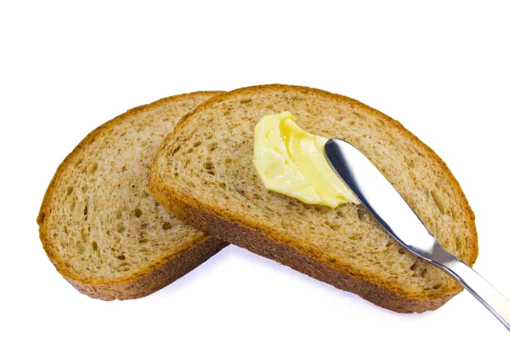 抹黄油的人在小麦面包上抹黄油。